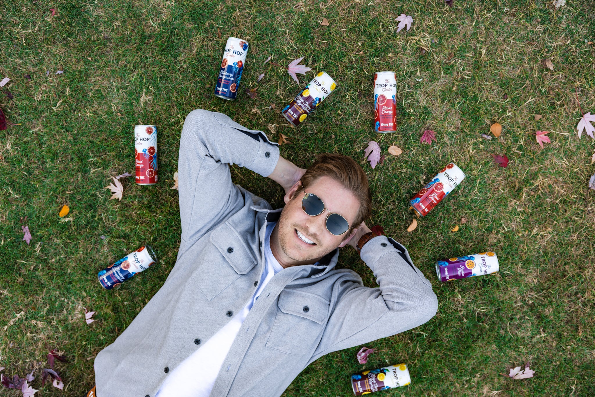 Austen Kroll from Bravo's Southern Charm lying on grass with colorful drinks around